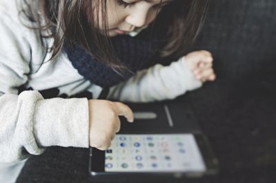 Close-up of cute girl using mobile phone on table at home