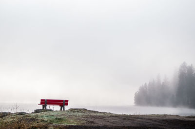 Red bench at beach against clear sky