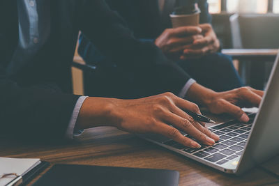 Midsection of man using mobile phone while sitting on table