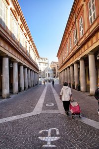 Rear view of woman walking in city against clear sky