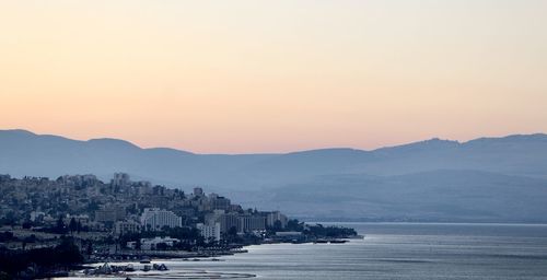 Scenic view of sea and buildings against sky during sunset