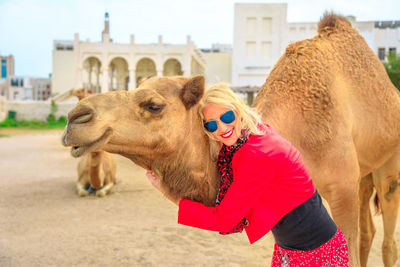 Portrait of woman embracing camel in city