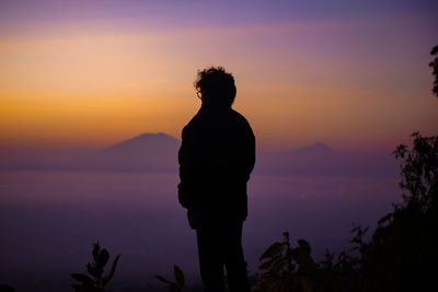 Silhouette man standing against orange sky