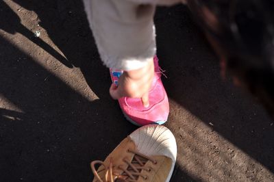 Cropped image of child pointing at shoe on road