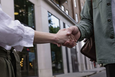 Man and woman doing handshake in front of building