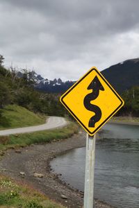 Information sign by road against sky