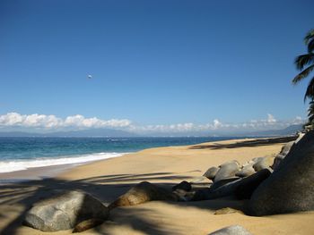 View of calm beach against blue sky