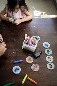 High angle portrait of family painting togeher using glitter glue arts and craft set.