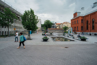 Woman walking in city against sky