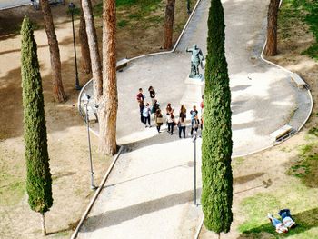 High angle view of students standing by statue on footpath in park