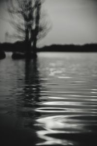 Reflection of silhouette trees in lake against sky