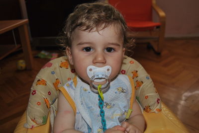 Portrait of cute baby boy sucking pacifier in walker at home