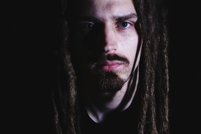 Close-up portrait of young man against black background