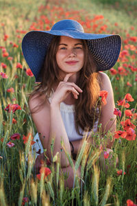 Portrait of a smiling young woman with yellow flowers on field