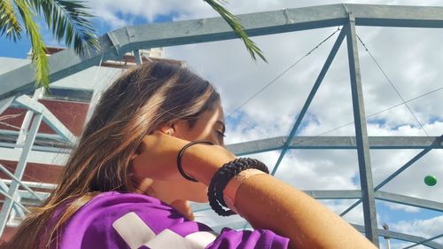 Young woman with umbrella against sky