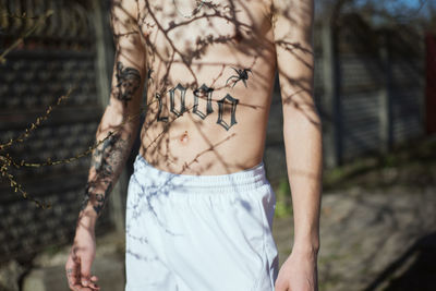 Midsection of shirtless man with tattoo