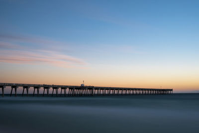 Pier over sea against sky during sunset