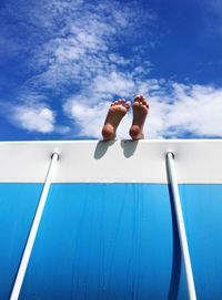 Low section of man against blue sky