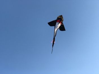 Low angle view of kite against clear blue sky