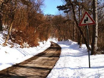 Road amidst snow covered trees against sky