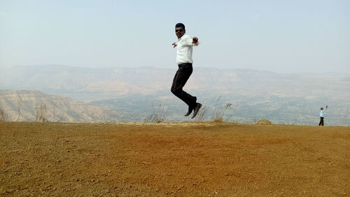 Full length of man jumping on landscape against sky