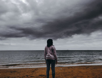 Rear view of woman standing against sea at beach