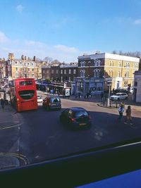 Cars on city street by buildings against sky