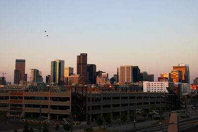 Modern buildings in city against clear sky during sunset