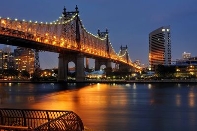 Illuminated bridge over river at night