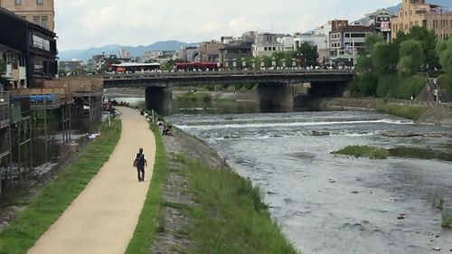 Footbridge over river in city against sky