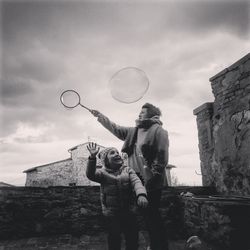 Full length of man and woman standing at bubbles against sky