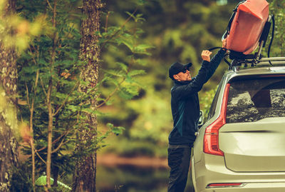 Man standing by car on tree