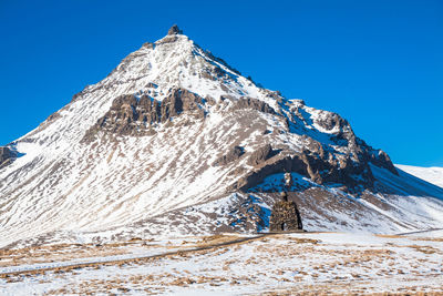 Low angle view of snowcapped mountain against clear blue sky