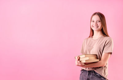 Portrait of a smiling young woman against pink background