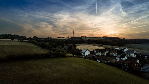 Houses on field against sky during sunset