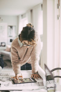 Midsection of woman standing by table at home