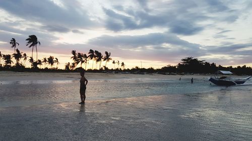 Silhouette people standing on beach against sky during sunset