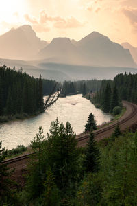 Scenic view of  railroad and river against mountains and sky