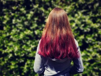 Rear view of girl with dyed hair standing against plants in park