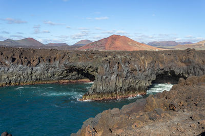 Scenic view of sea and rocky mountains against sky