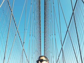 Low angle view of man on bridge against blue sky