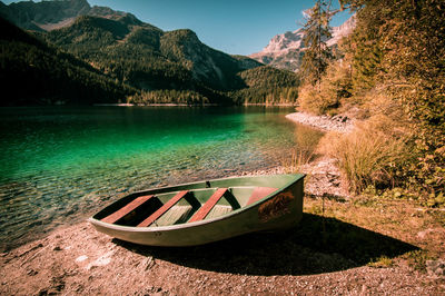 Boat moored by lake against mountains