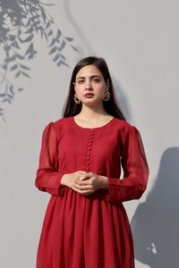 Portrait of young woman standing against white background