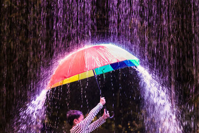 Boy spinning umbrella during rainy season