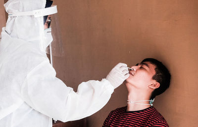 Side view of young man swab test with nurse 