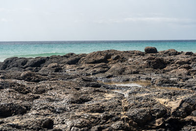 Scenic view of rocks on beach against sky