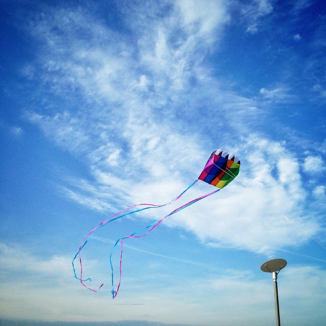 low angle view, sky, blue, cloud - sky, cloud, multi colored, pole, wind, day, flag, fun, identity, mid-air, outdoors, balloon, sport, hanging, childhood, no people, cloudy