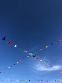 Low angle view of flags hanging against clear blue sky