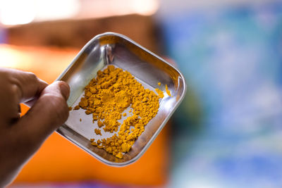 Close-up of person holding spice in container