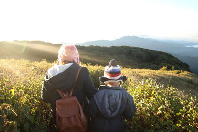 Rear view of people on field against sky